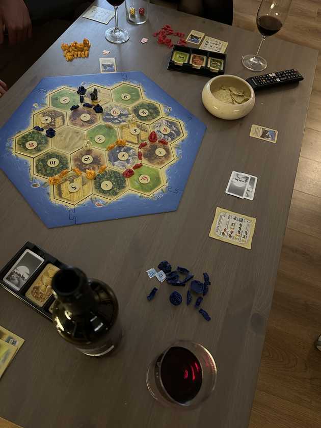 Catan game board, wine and chips.